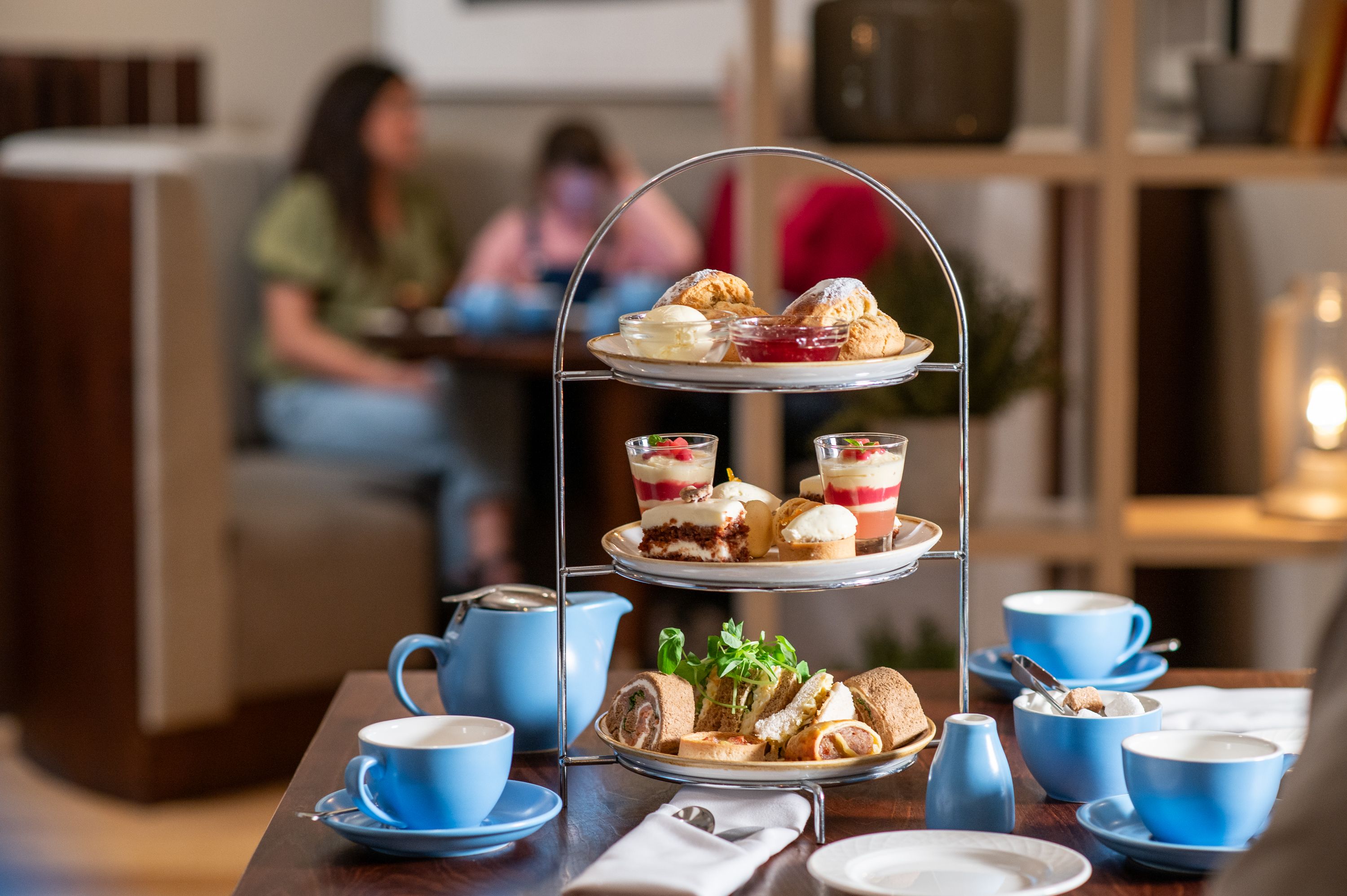 Indoor afternoon tea with blue tea cups and a family in the background